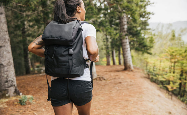 Woman wearing the Shadow Guide 33 on a hike; full view of the bag and label.